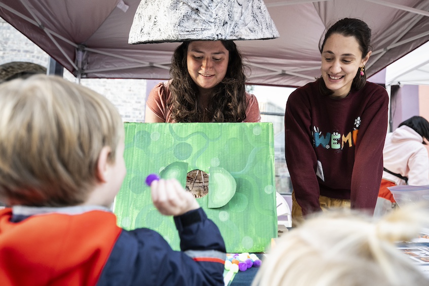 “It’s All Fun(gi) and Games…” — Wearing mushroom-inspired headgear, graduate students from What’s Eating My Plants (WEMP), an outreach group in the department of plant pathology at UW–Madison, encourage a child to “infect” a plant with a fuzzy “spore” during Science on the Square. (Photo by Jeff Miller / UW–Madison)
