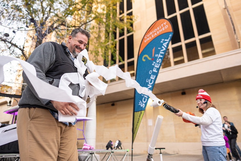 “Fitting for a Free Mummy Costume” — An attendee at Science on the Square volunteers to be transformed into a mummy through the magic — or science — of toilet paper and a leaf blower during the Wonders of Physics show. (Photo by Romulo Ueda Photography)