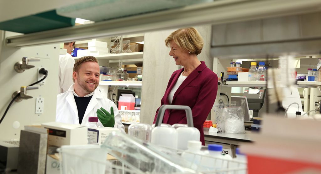 Mateusz Manicki, a postdoctoral fellow in the Pagliarini Lab at Morgridge, discusses his research with Tammy Baldwin during her visit.